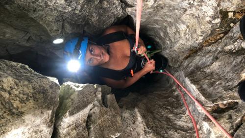 Frau steigt mit Seil in der Donini-Höhle ab