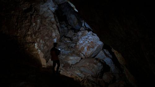 Escursionista cammina all'interna della buia grotta Sa Nurre de Su Hoda a Oliena