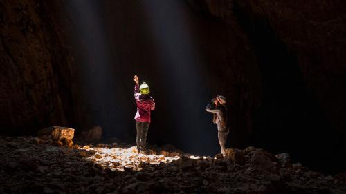 Due escursioniste osservano il fascio di luce all'interno della grotta Sa Nurre de Su Hoda a Oliena