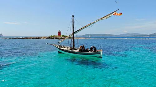 Latin sailboat sailing in the crystal-clear waters of Alghero