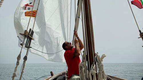 Man adjusting sails while sailing in the Port of Alghero