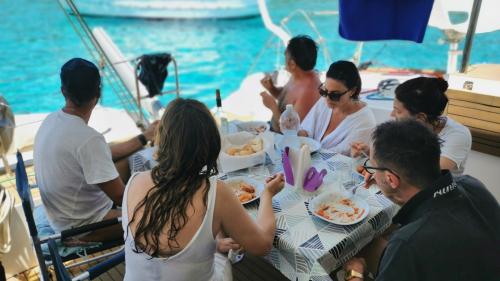 Menschen an Bord des Katamarans beim Mittagessen in einer Bucht auf der Insel Asinara