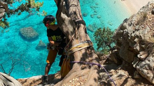 Wanderer beim Abseilen mit dem türkisfarbenen Meer des Golfs von Orosei im Hintergrund