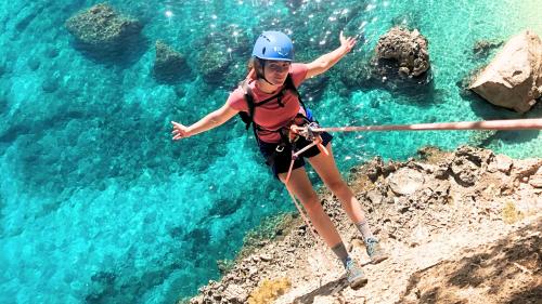 Hiker during a rope abseil with the turquoise sea of the Gulf of Orosei behind him