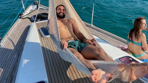Junge entspannt sich in einer Hängematte an Bord eines Segelboots in Cagliari