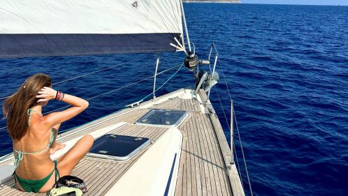 Ragazza a bordo di una barca a vela ammira il mare blu di Cagliari