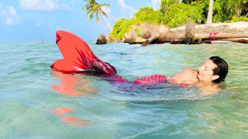 Mädchen als Meerjungfrau verkleidet schwimmt im kristallklaren Meer von Cagliari