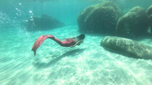 Tourist schwimmt mit Meerjungfrauenschwanz im Meer des Golfs von Cagliari