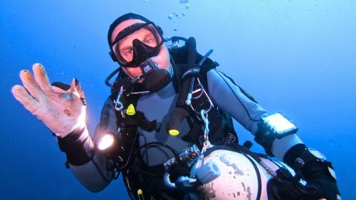 Person waving while diving in the waters of Cagliari