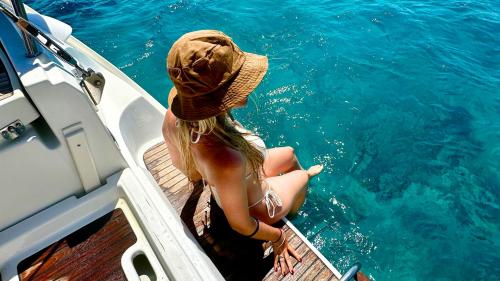 Girl relaxes at stern of sailboat from Cannigione