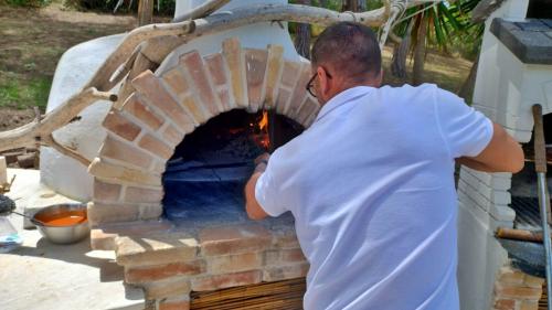 Chef prepares pizzas in wood-fired oven in ancient villa in Sorso