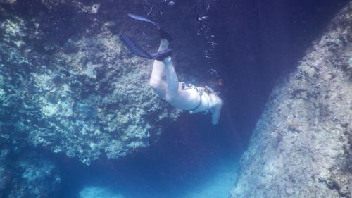 Fille en costume faisant de la plongée avec masque et tuba parmi les rochers du golfe d'Orosei