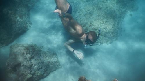 Junge beim Schwimmen auf dem felsigen Meeresgrund von Cala Gonone