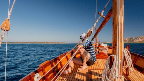 Junge sitzt im Boot und sieht Asinara am Horizont