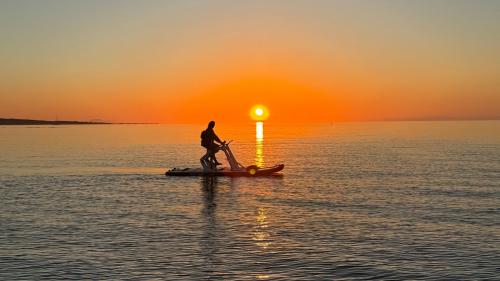 Personne pédalant sur l'eau au coucher du soleil à Stintino