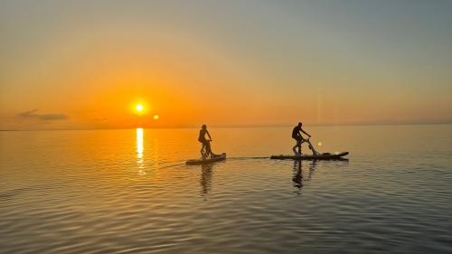 Des personnes sur des vélos aquatiques alors que le soleil se lève dans la mer de Pelosa