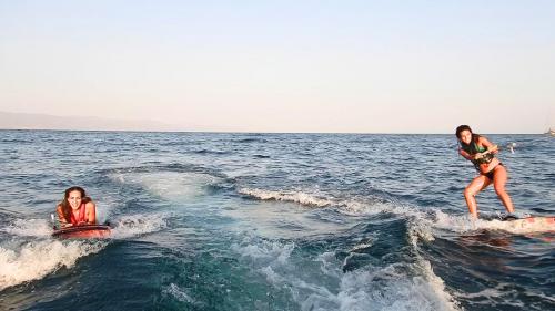 Des garçons s'adonnent à des jeux d'eau tirés par un bateau à Cagliari