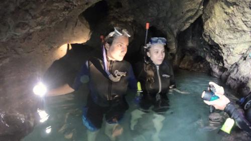 Guide with hikers with snorkelling equipment inside a cave accessible only by sea 