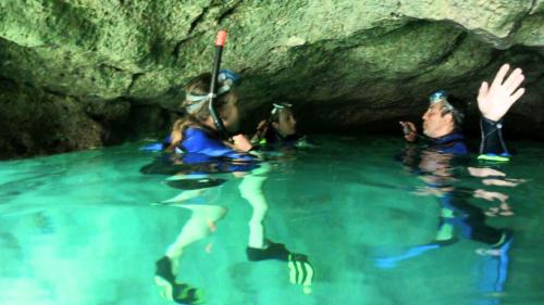 Guide avec des randonneurs équipés de matériel de plongée en apnée à l'intérieur d'une grotte accessible uniquement par la mer 