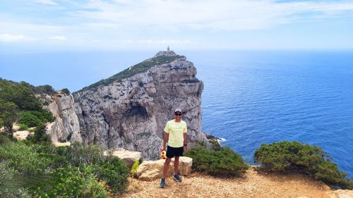 Randonneur lors d'une expérience de vélo électrique avec les falaises derrière lui et la mer bleue d'Alghero