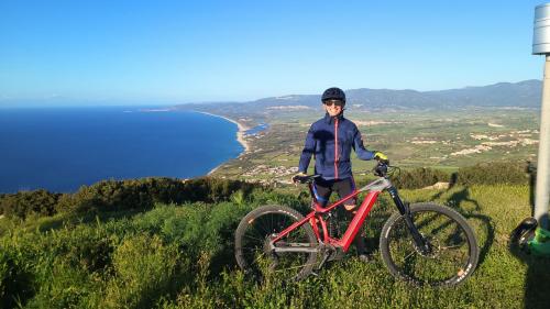 Hiker on ebike and panorama overlooking the coast of the Gulf of Asinara