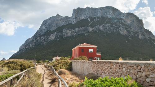 Rotes Haus mit der Insel Tavolara im Hintergrund im Nordosten Sardiniens