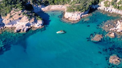 Barca a motore vista dall'alto che sosta tra le coste di Alghero