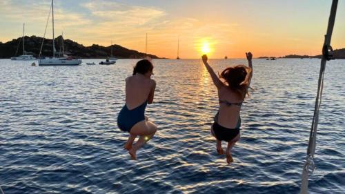 Ragazze mentre si tuffano dalla barca durante il tour in barca a vela nell'arcipelago di La Maddalena nel nord-est della Sardegna