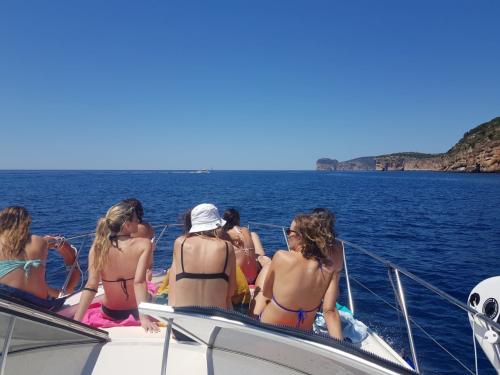 Persone a prua durante escursione in barca nella costa di Alghero