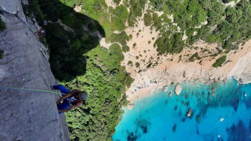 A man climbs the Needle of Goloritzè and views of the beach