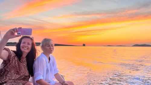 Zwei Freunde machen ein Foto mit dem Sonnenuntergang über dem Meer