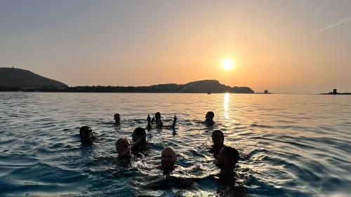 Glückliche Menschen schwimmen bei Sonnenuntergang in La Pelosa