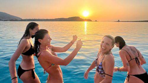 Four friends joke on the catamaran in La Pelosa at sunset
