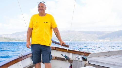 The captain steers the sailing ship through the azure waters of the Gulf of Asinara